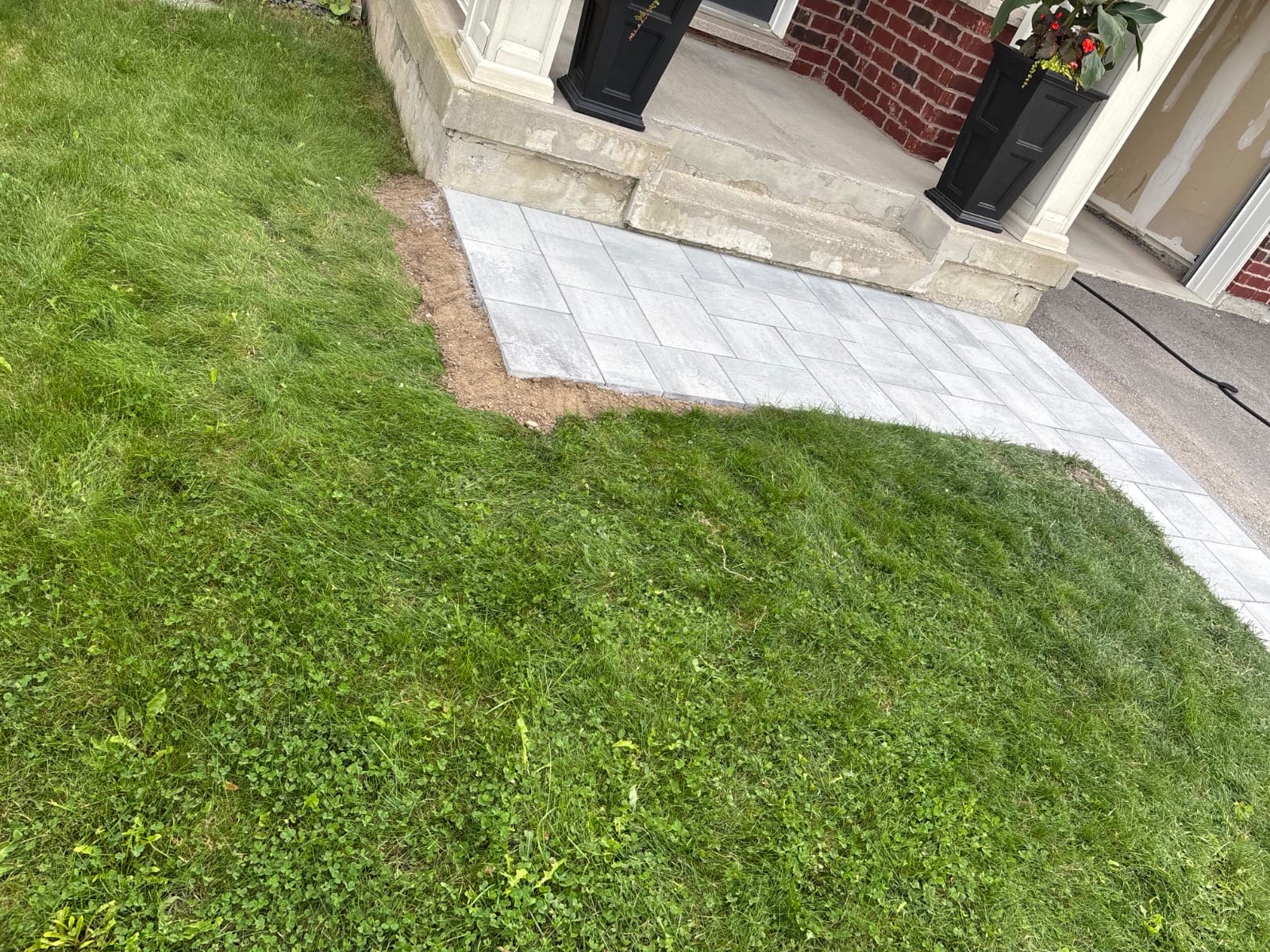 Grey paving stones curve from the front steps toward the driveway